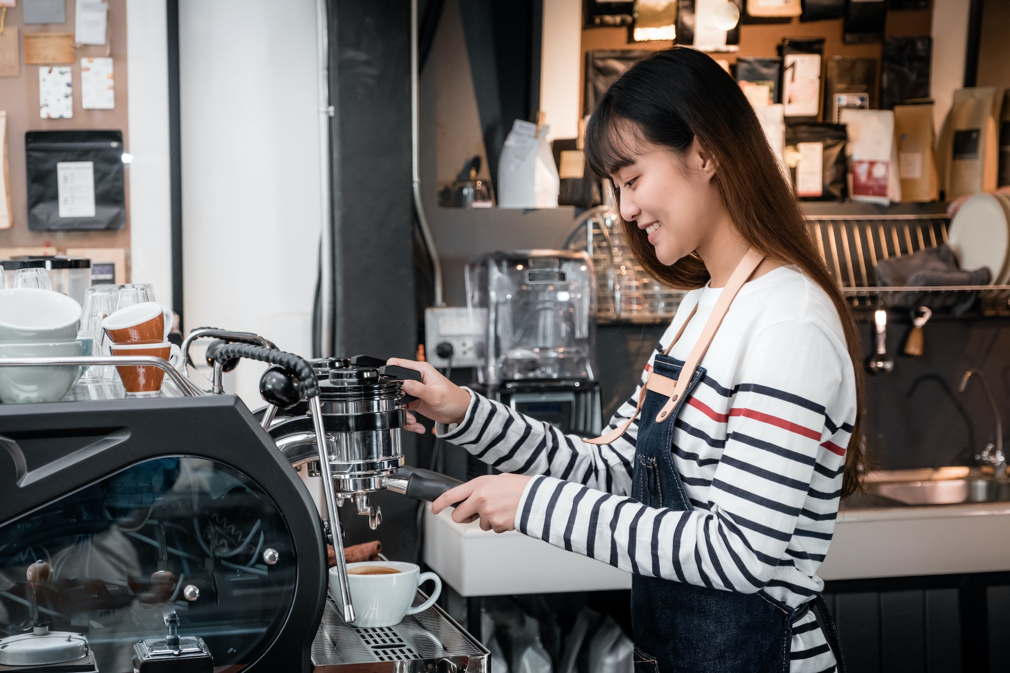 Asia female Barista wear apron making hot coffee menu for customer